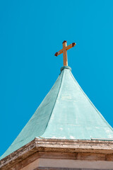 The cross standing tall on the green roof of the church © 子程 龚