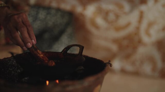 Close-up of traditional Javanese batik making process, melting wax in a canting over a small flame