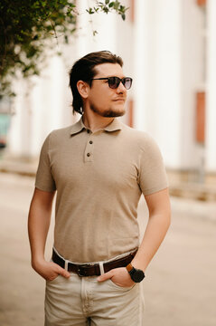 Man Looking Left Beige Polo Stands Thoughtful On Treelined Walkway With Hands In Pockets, Architectural