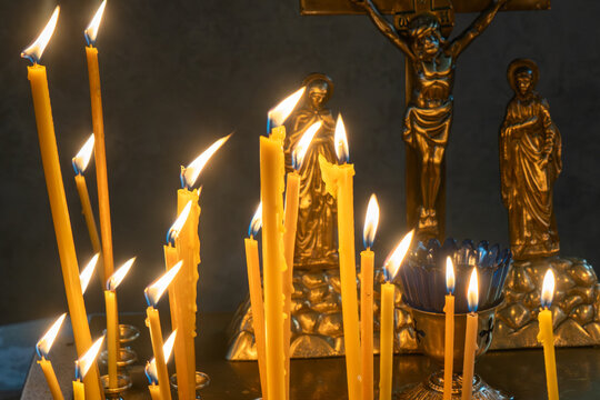 Burning church candles on a gold stand in front of the orthodox crucifix. Memorial candles burning in an orthodox temple during the christian liturgy of the great lent.