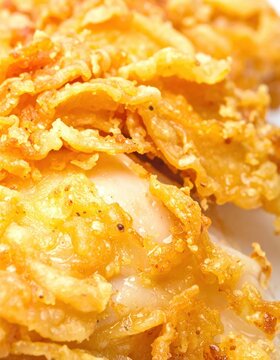 Extreme closeup of crispy golden brown fried chicken showing textured breading and juicy meat layer