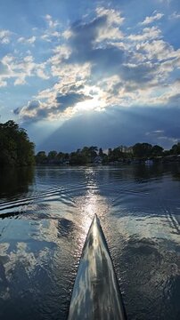 Sculling boat flows along river with sunset behind