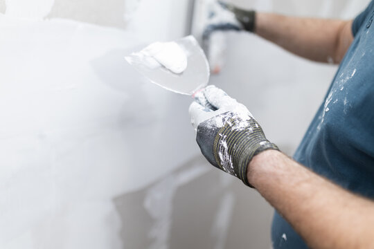 Worker Holding Putty Knife With Plaster Compound