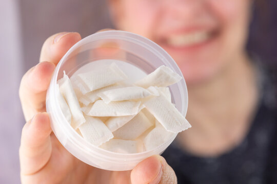 person holding open container of white nicotine pouches or snus portions close up concept of smokeless tobacco, nicotine delivery, tobacco alternatives