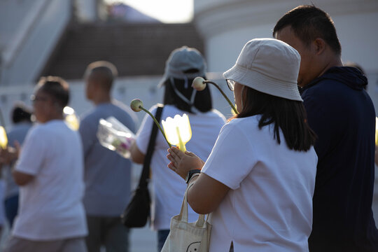 Believers walking in candlelight procession around Buddha statue on Makha Bucha Day, side view, at Phutthamonthon.