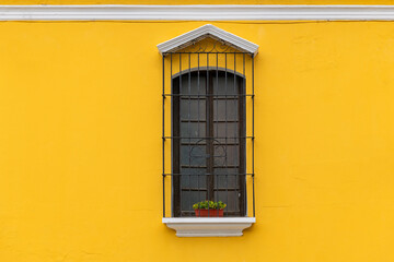 Fototapeta premium Yellow facade with colonial style window, Antigua, Guatemala.