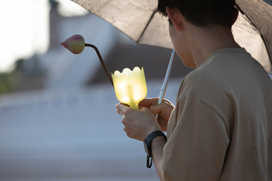 Male believer walking in candlelight procession around Buddha statue on Makha Bucha Day at Phutthamonthon, close up.