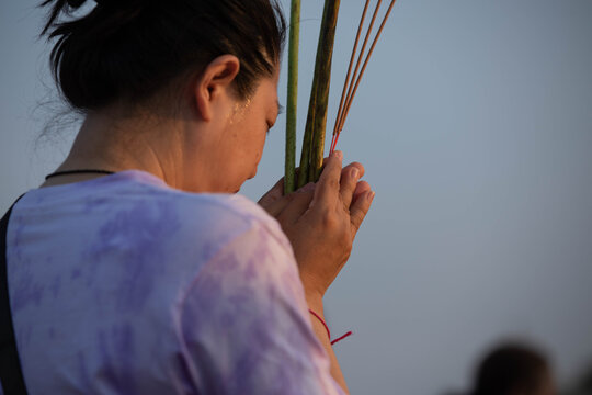 Thai female believer walking in candlelight procession around Buddha statue on Makha Bucha Day, close up, at Phutthamonthon.