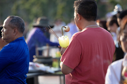 Thai people gathering for candlelight procession around Buddha statue on Makha Bucha Day, rear view.