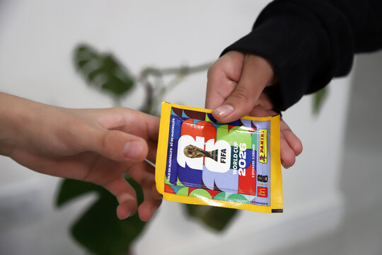 
Children holding a pack of stickers from the 2026 FIFA World Cup. Panini sticker pack in collaboration with McDonald's