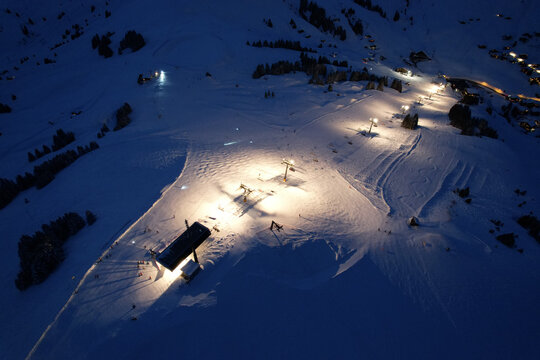 Aerial view of Les Crosets ski resort at night with illuminated ski slopes and chairlifts among the snow-covered mountains in Val-d'Illiez, Valais, Switzerland.
