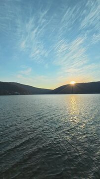 Sun dips behind hills, painting sky with soft gold. Bovan lake, Serbia