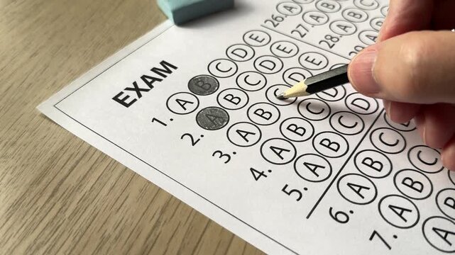 Hand choosing answer on multiple choice exam sheet with pencil. Concept of decision making, testing, uncertainty, and academic evaluation