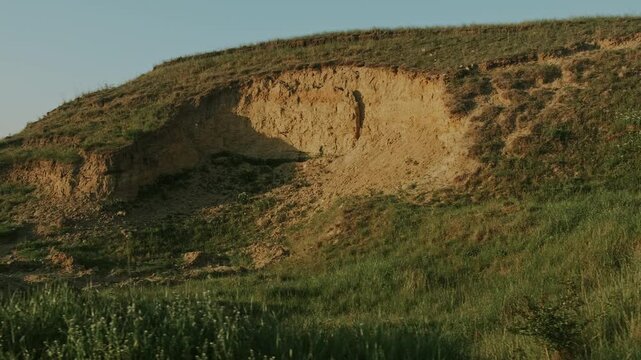 Earthen Hollow With Grassy Rim Under Warm Sun, Eroded Cavity And Layered Soil Exposed, Panoramic View