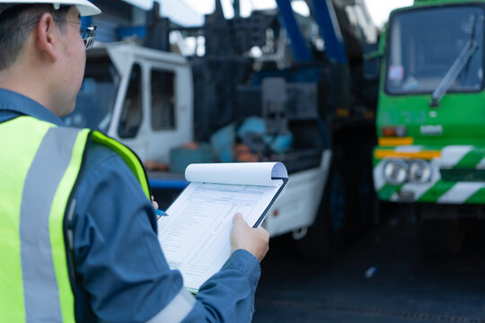 Engineer holding a checklist during crane inspection inside a maintenance bay, supporting safety compliance, equipment assessment, and heavy lifting readiness