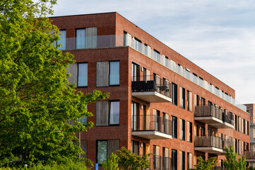 Modern Red Brick Residential Building with Balconies,New Apartment Block Architecture Surrounded by Greenery,Newly Built Residential Complex in a Modern City District © Anna Kondratiuk