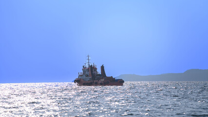 Obraz premium Tugboat sails calmly across shimmering ocean waters