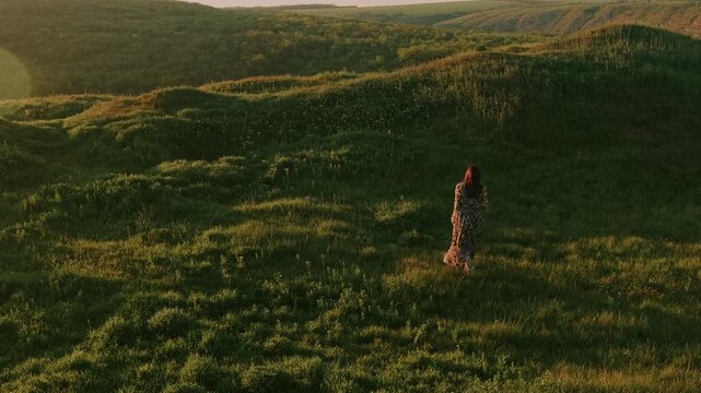 Woman Walking Through Grassy Dunes Toward Distant Hills At Sunset, Soft Golden Light, Solitary Silhouette,