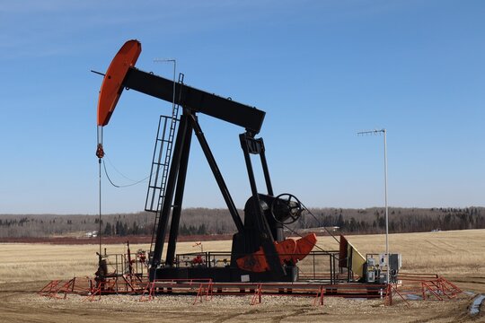 A pumpjack, or nodding donkey on a crude oil well pumping oil into a pipeline. The jack sits on the Canadian prairies, which is a common sight there. 