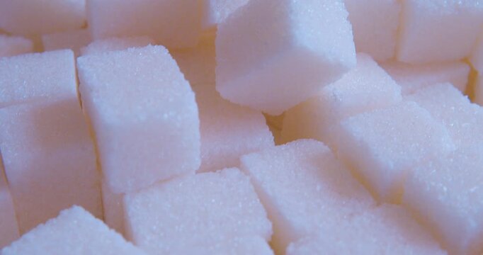 Close-up of white sugar cubes lying on a neutral surface bathed in soft, diffused morning sunlight. 