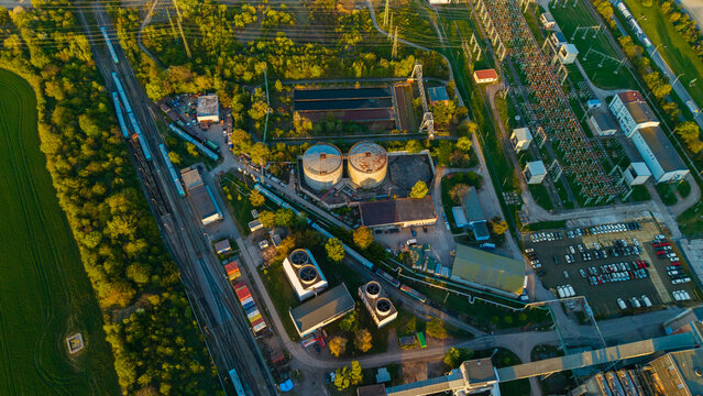 Aerial view of Malesice Infrastructure Objects featuring industrial tanks, cooling towers, and railway tracks under golden hour light in Hlavni mesto Praha, Hlavni mesto Praha, Czechia.