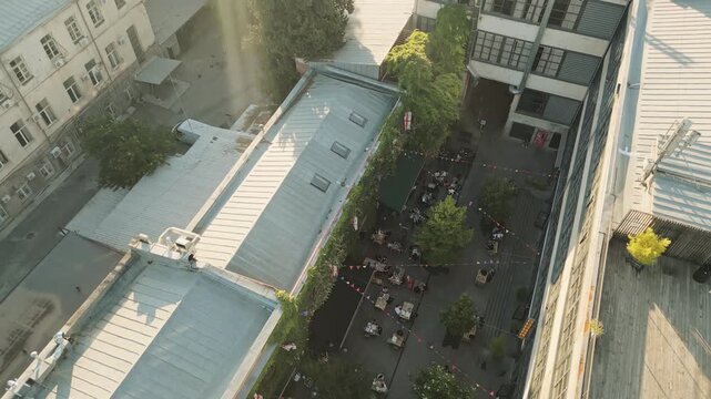 Tbilisi, Georgia - 1st july, 2025: Aerial Fabrika courtyard in Tbilisi, vibrant social hub with outdoor seating, trees, string lights, groups of guests enjoying the lively atmosphere in heart of city