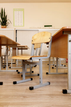 Empty wooden chair and desks in school classroom interior. Primary education furniture background. Back to school concept, elementary learning workspace, classroom, nobody, indoor, study, room