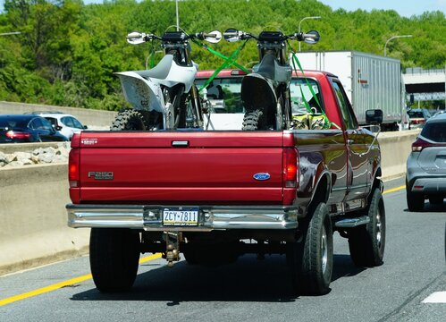 Newark, Delaware, U.S - May 5, 2026 - A red Ford F-250 hauling two dirt bikes in the truck bed while traveling on I-95 North