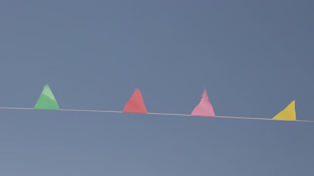 Bright party pennants fluttering upwards in wind against clear blue sky