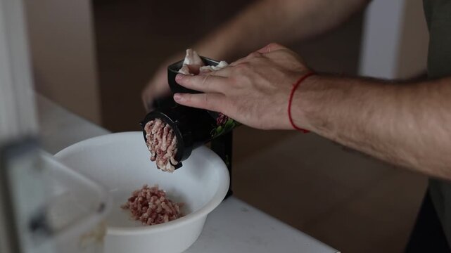 Raw pork is minced in meat grinder