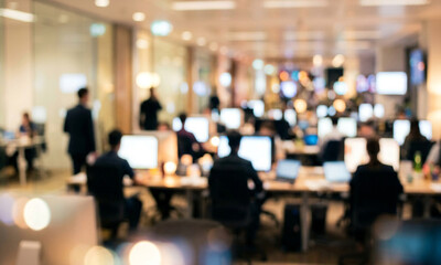 Fototapeta premium An office environment with multiple workstations, blurred figures of employees engaged in work, and illuminated screens, creating a dynamic corporate atmosphere.