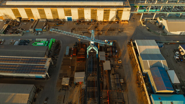 Aerial view of Malesice Infrastructure Objects featuring a large blue crane, industrial warehouses with solar panels, and storage yards at sunset Prague, Prague, Czechia.