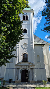 A vertical close up of the white front facade and bell tower of the historic Church of Saint John the Baptist in Nova Ves under a blue sky in Zagreb