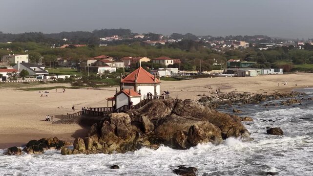 Waves crash around historic Senhor da Pedra Chapel Porto Portugal
