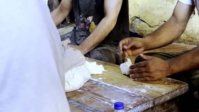 Making bread in traditional clay tandoor oven using wood fire, rural cooking method preparing fresh flatbread in village kitchen