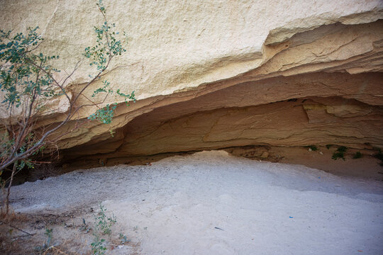 Cappadocia Tuff Rock Cave Overhang with Sparse Shrubs and Gravel Floor