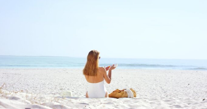 Woman, relax and sunscreen by ocean with summer holiday, UV protection or skincare outdoor for wellness. Back, space and person apply spf cream by sea for dermatology, sunburn prevention or vacation.
