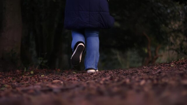 Woman running through dark woodland
