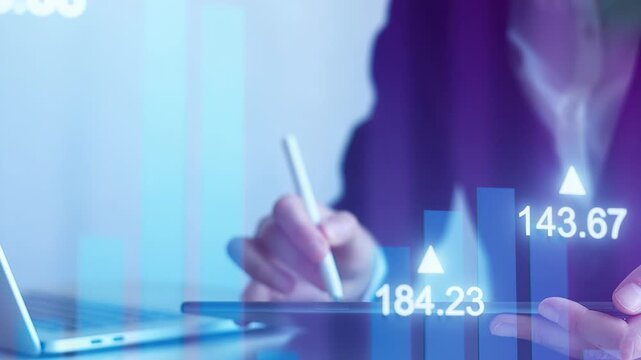 Business professional analyzes market data using a digital tablet while working in an office setting during the afternoon.