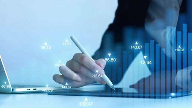 Businessperson writes on tablet with data visualization in background during office hours in a modern workspace.