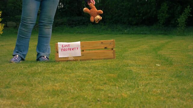 Dropping lost children toy teddy bear into lost property box