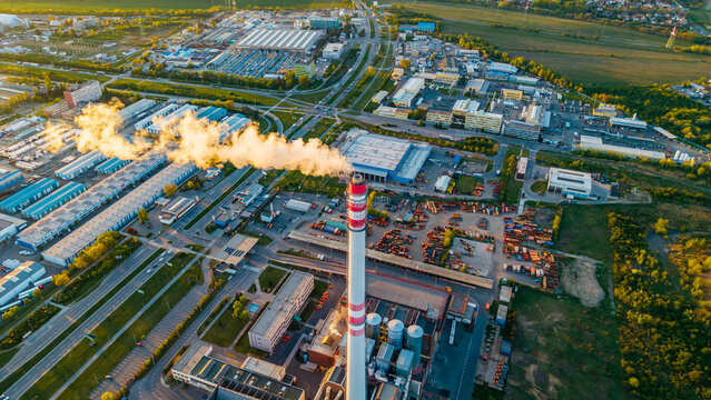 Aerial view of Malesice Infrastructure Objects featuring a tall industrial chimney emitting smoke over warehouses and roads in Hlavni mesto Praha, Hlavni mesto Praha, Czechia.
