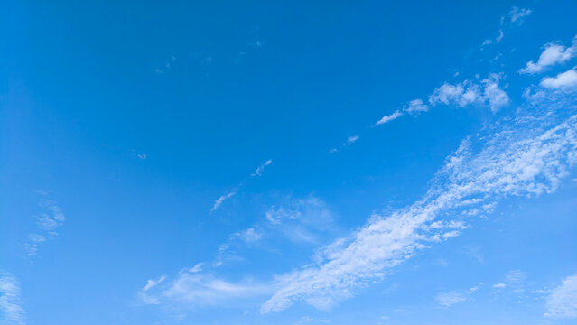 Clear blue sky with scattered white clouds on bright day.