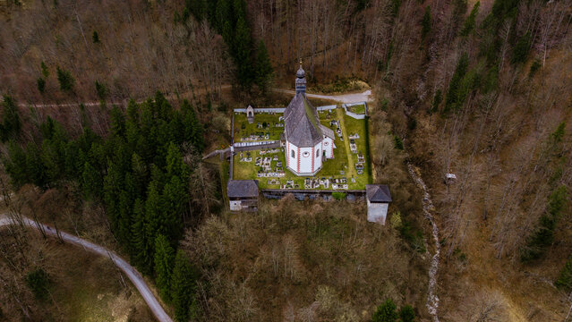 Aerial view of the historic Bergkirche Klaus church and its walled cemetery nestled within a dense forest Klaus an der Pyhrnbahn, Upper Austria, Austria.