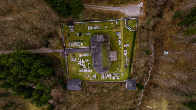 Aerial view of the historic church and cemetery at Klaus Castle surrounded by a stone wall and dense forest in Klaus an der Pyhrnbahn, Upper Austria, Austria.