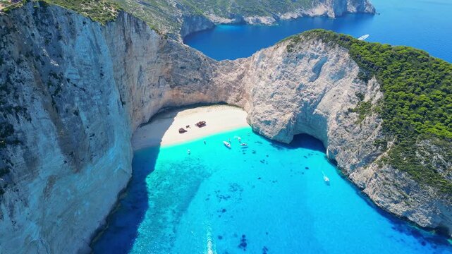 Spectacular view of the iconic Shipwreck beach in Navagio Bay, Zakynthos. Famous rusted boat on white sand surrounded by massive limestone cliffs and turquoise Ionian Sea water.