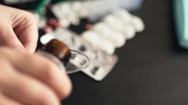Macro shot of measuring precise dosage of liquid medication syrup into a spoon with blurred pills on the background, pharmaceutical concept, 4K UHD