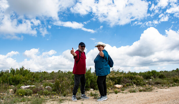 Pareja de jubilados en la monta&ntilde;a un d&iacute;a soleado con nubes.