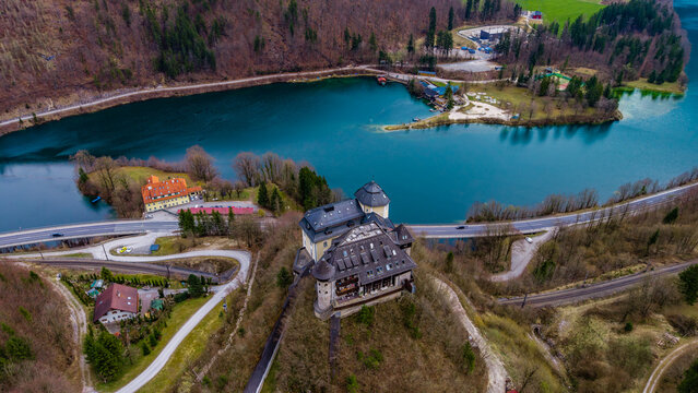 Aerial view of Klaus Castle perched on a hill overlooking the turquoise waters of the Steyr river and Klauser Stausee reservoir in Klaus an der Pyhrnbahn, Upper Austria, Austria.