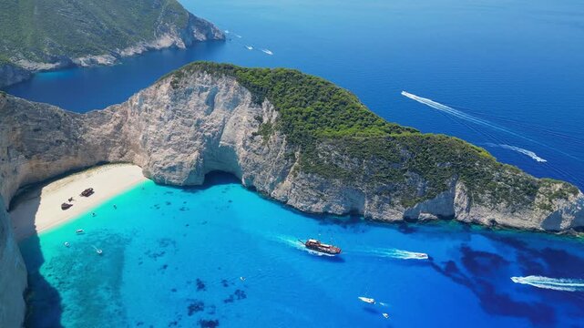 Spectacular view of the iconic Shipwreck beach in Navagio Bay, Zakynthos. Famous rusted boat on white sand surrounded by massive limestone cliffs and turquoise Ionian Sea water.